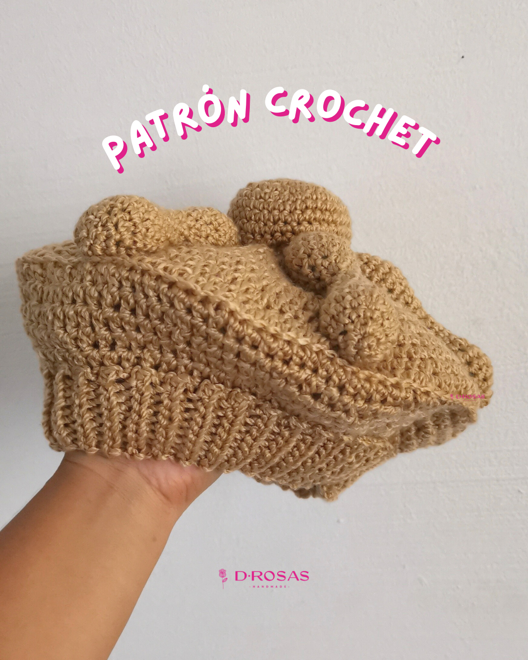 Boina en forma de pan de muerto tejida en crochet o gancho, color pan detalles en relieve que asemejan la forma del pan representativo de día de muertos. Letras que dicen Patrón crochet en la parte superior.